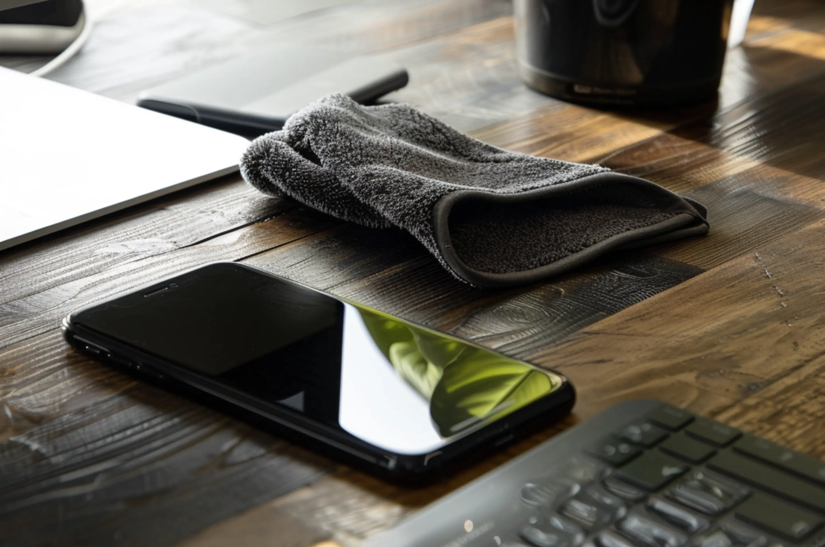 Das iPhone liegt auf dem Tisch. Daneben liegt ein Tuch zum reinigen.