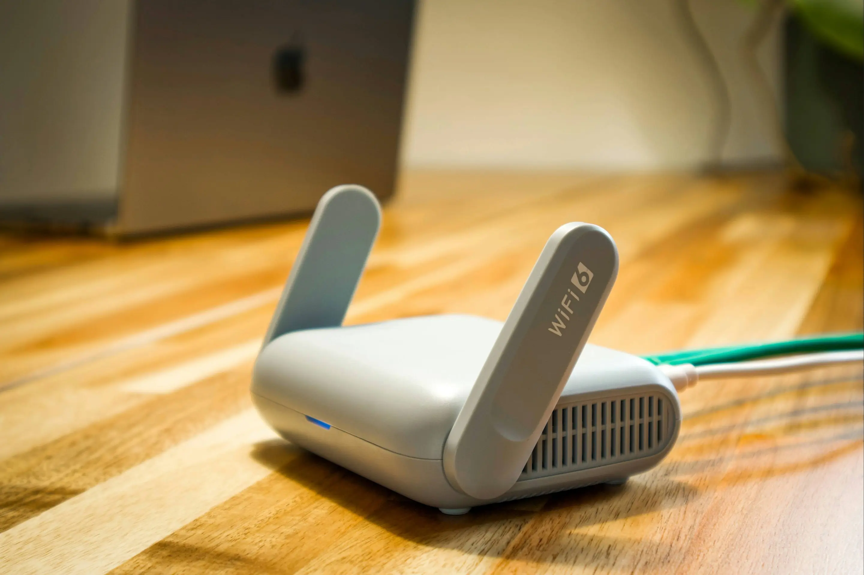 Weißer Wlan-Repeater steht auf einem Holztisch und ist mit Kabeln angeschlossen