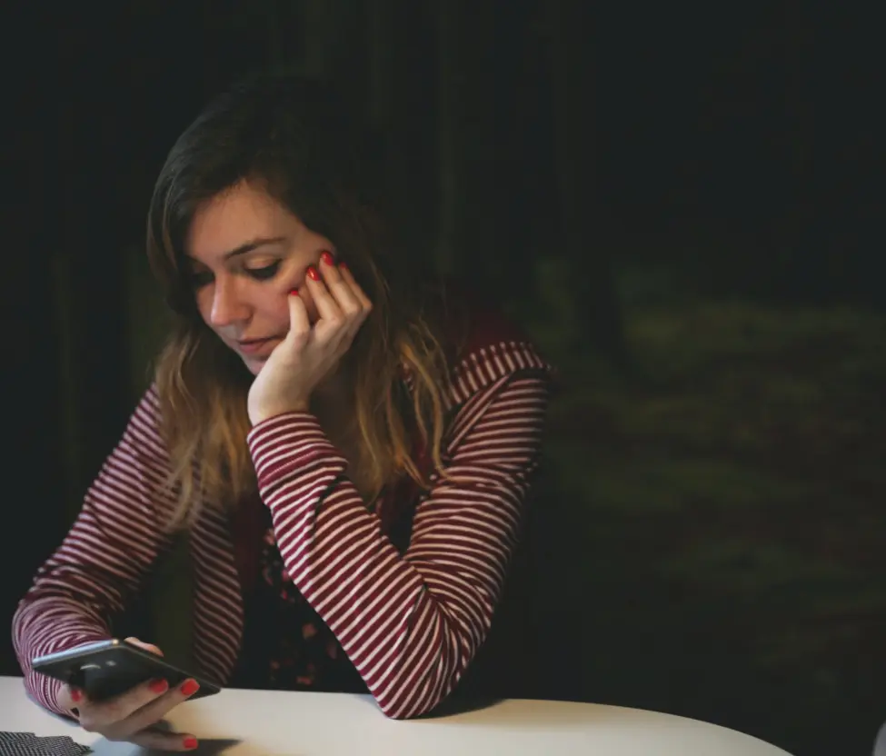 Frau sitzt vor ihrem Handy