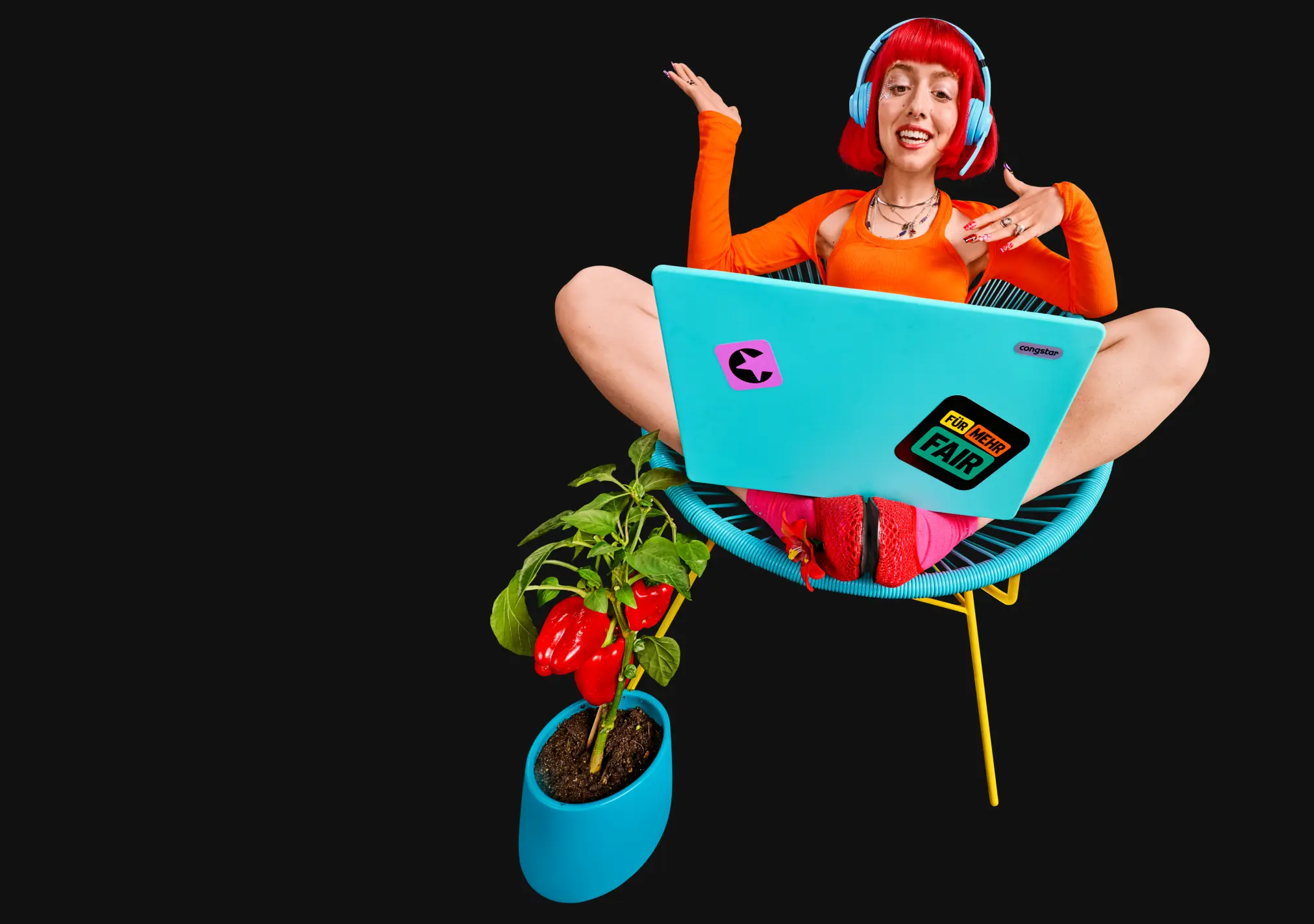 Lächelnde Person sitz mit Laptop und Kopfhörern auf einem Stuhl.