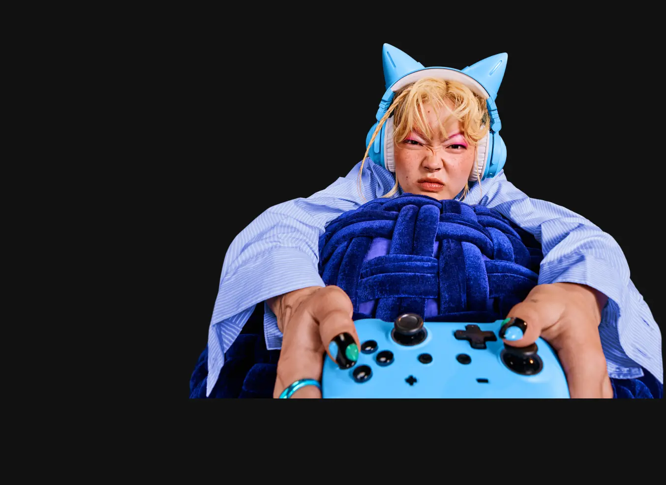 Eine Person trägt ein blaues Kostüm mit Katzenohren und schaut konzentriert. Der Hintergrund ist schwarz.