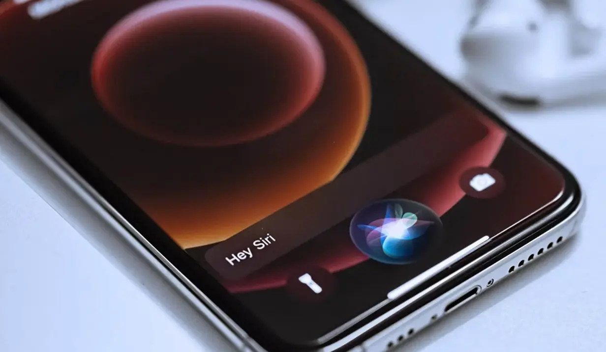 Nahaufnahme eines Smartphones mit aktiviertem Sprachassistent. Auf dem Bildschirm steht „Hey Siri“.
