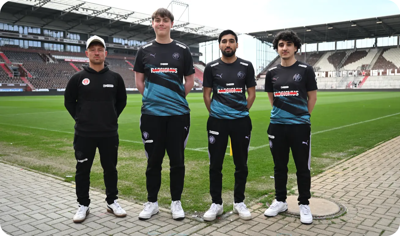 Ein Trainer und drei eFootball-Spieler stehen im Millerntor-Stadion