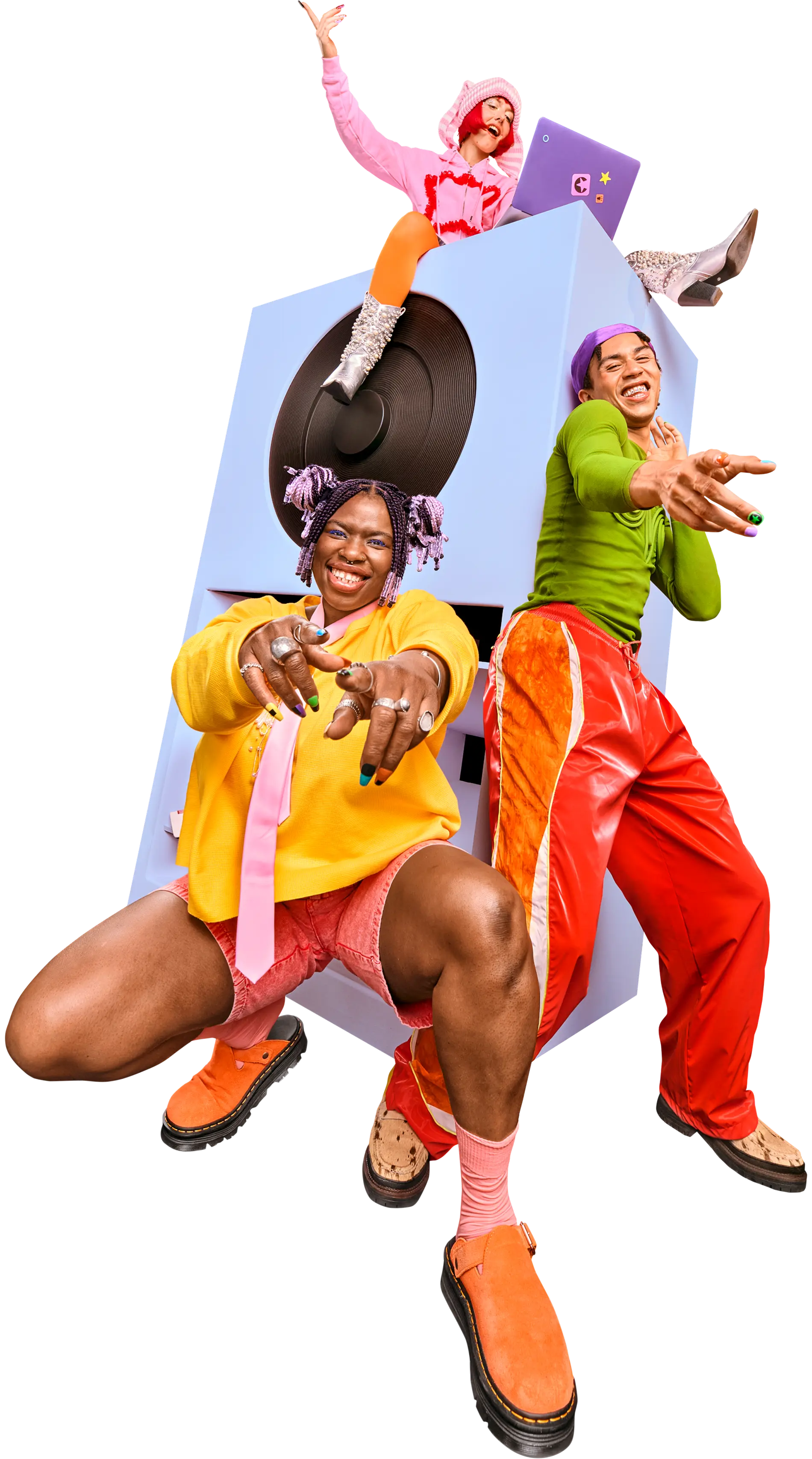 Drei Personen in bunten, ausgefallenen Outfits posieren energiegeladen um einen großen, hellblauen Lautsprecher. Eine Person hockt im Vordergrund und zeigt in die Kamera, eine zweite lehnt lächelnd daneben, und die dritte sitzt mit einem Laptop oben auf dem Gerät und hebt jubelnd den Arm.