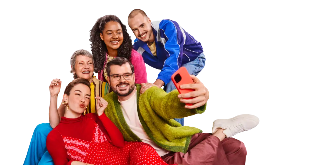 Eine Gruppe von fünf Personen in bunten Outfits macht gemeinsam ein Selfie auf einem grünen Sofa.
