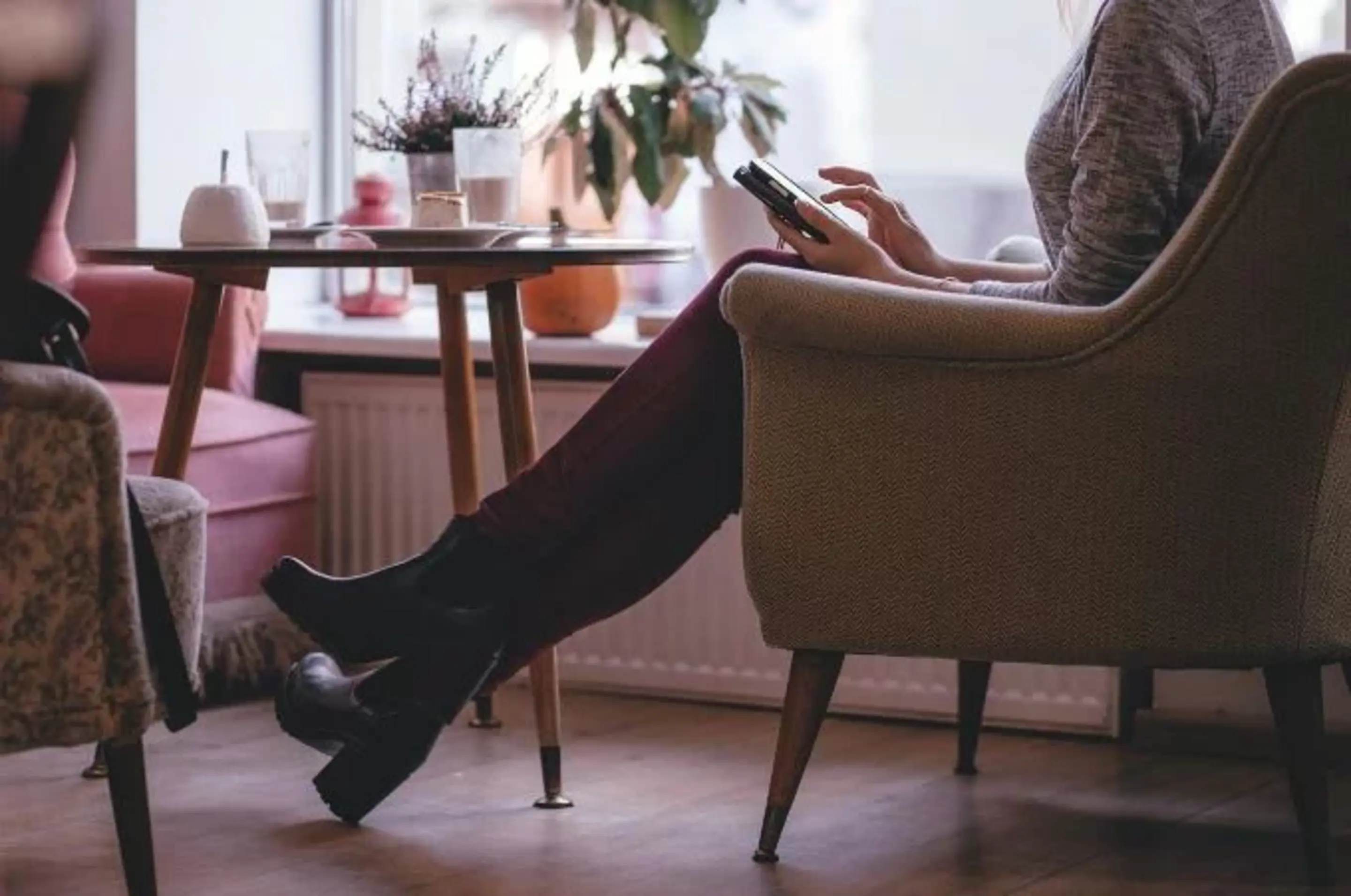 Person sitzt mit Handy auf einem Sessel