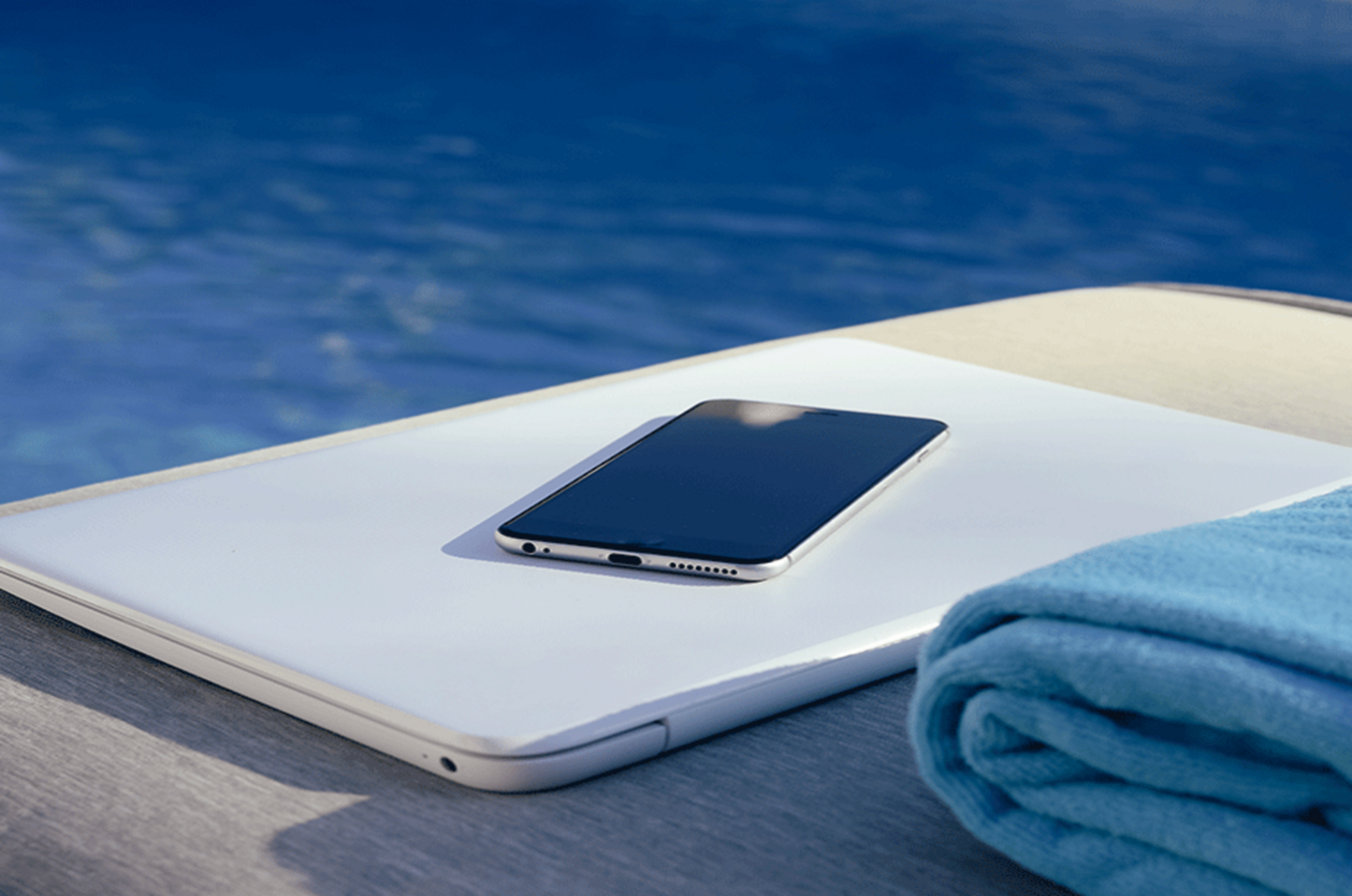 Handy liegt in der Sonne neben einem Pool