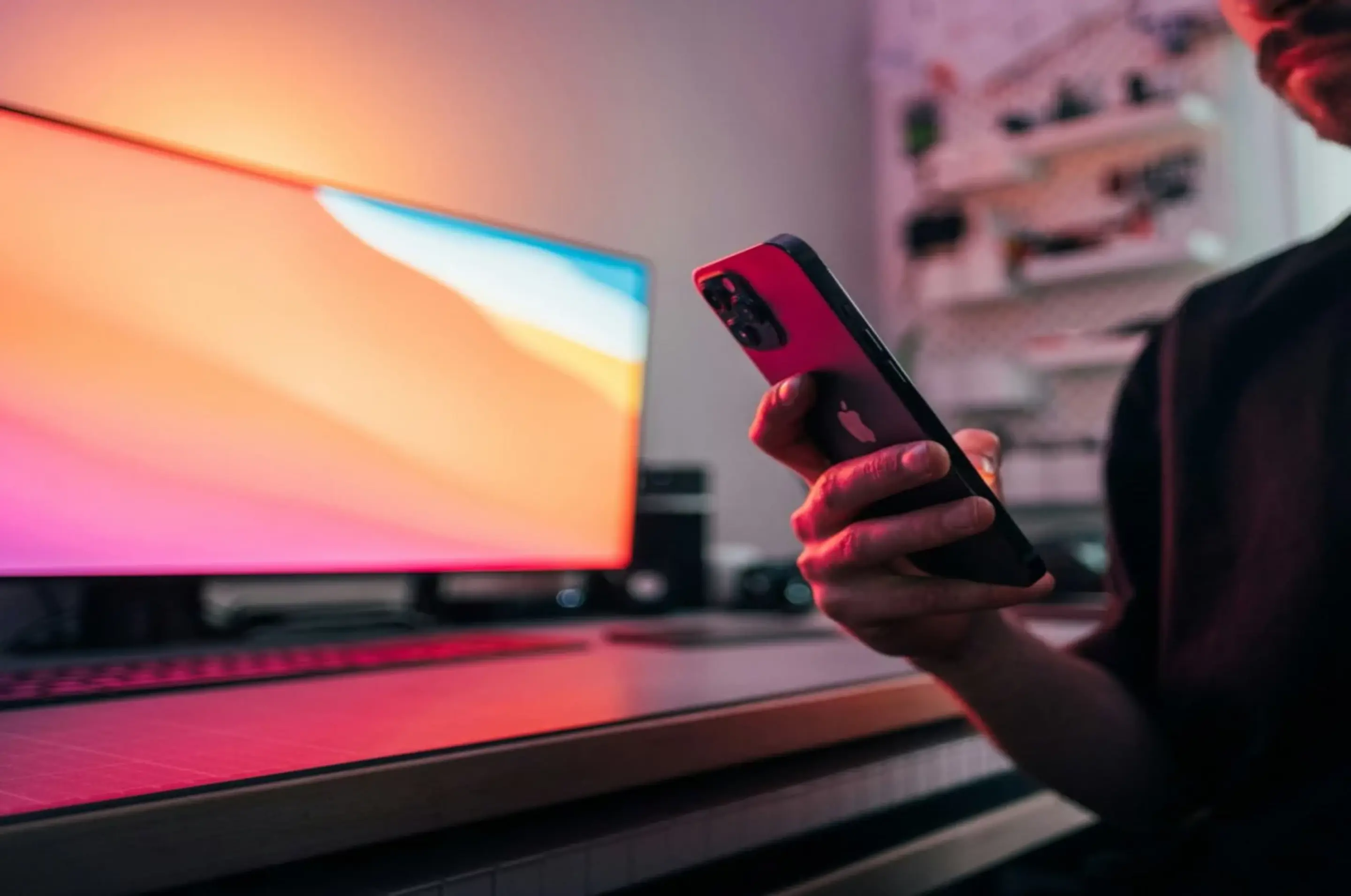 Heller Bildschirm im Hintergrund und Person im Vordergrund hält Handy in der Hand
