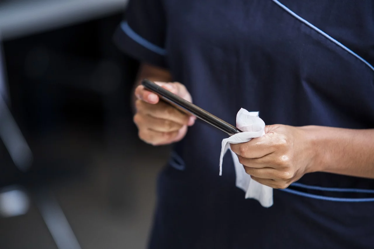 Person reinigt Handy mit Tuch